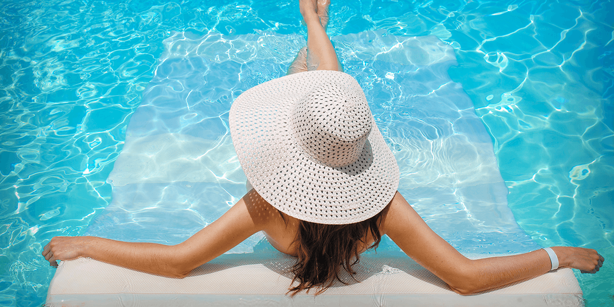 A woman wearing a hat relaxing in a pool
