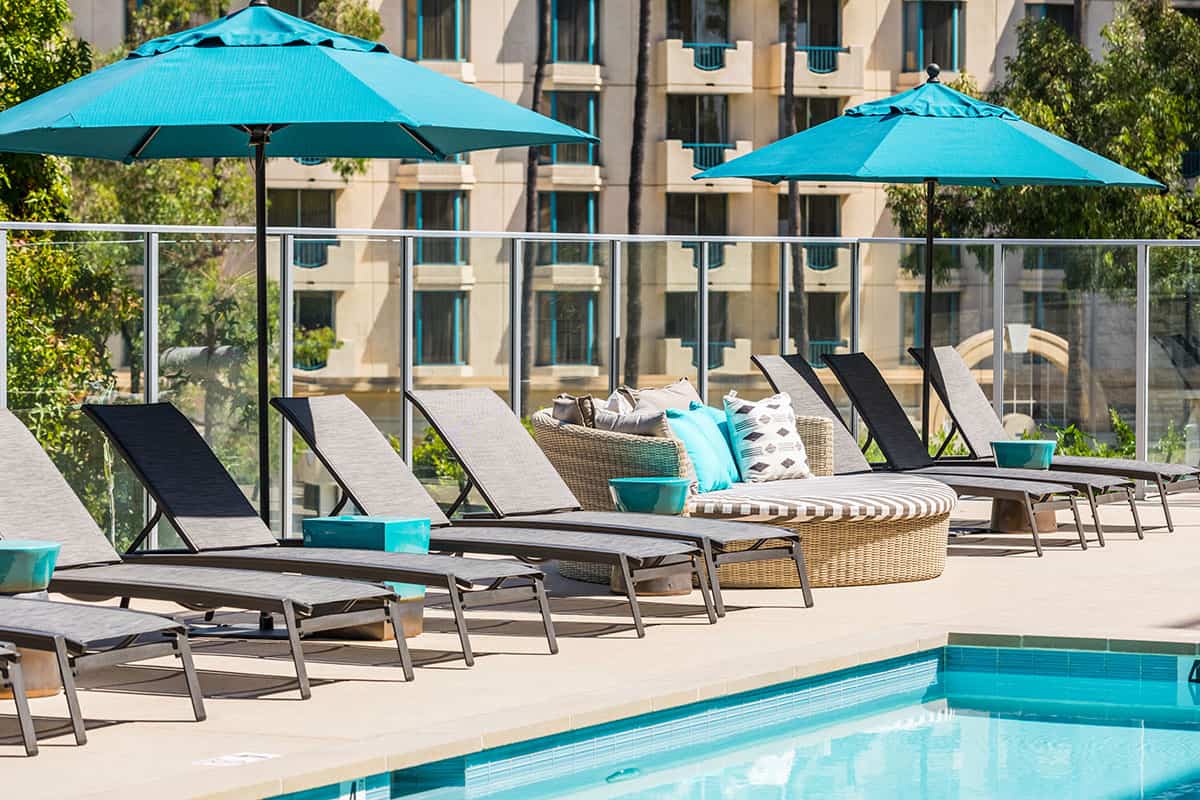 The pool area at 580 Anton Apartments in Costa Mesa, showcasing a beautiful pool surrounded by seating areas and lush landscaping.