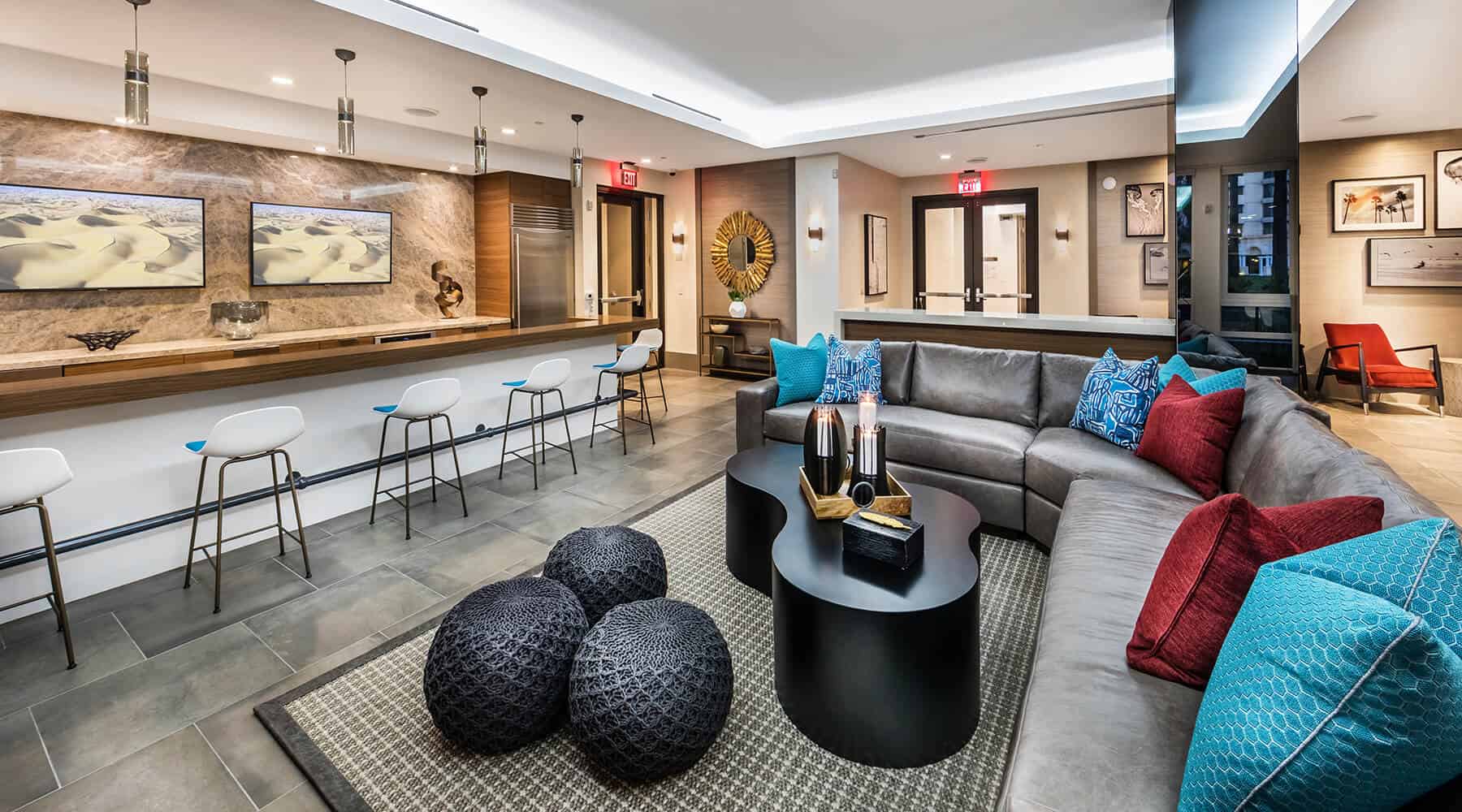 A modern apartment lounge with a sectional sofa, bar stools, a sleek counter, and stylish decor.