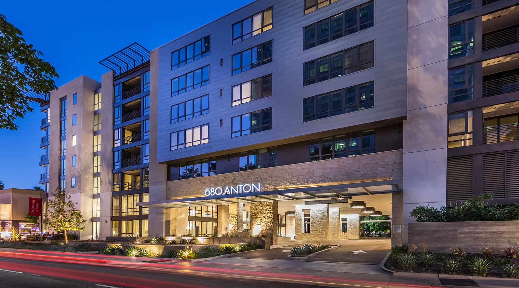 Exterior view of 580 Anton at night with illuminated signage and surrounding landscaping.